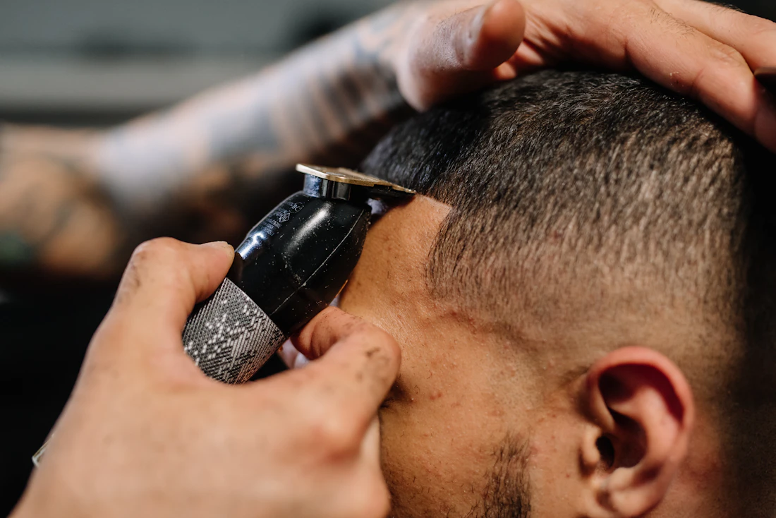 Barber taking a clipper up the side of a client's fade