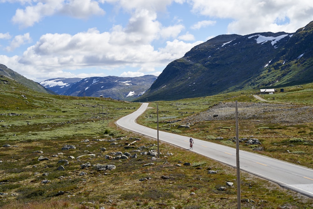 a person walking on a road in a valley between mountains