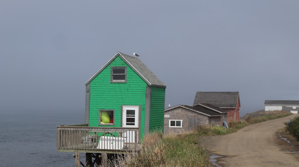 a green house on a hill by the water