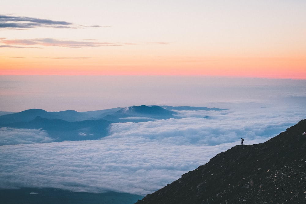 a person standing on a cliff above the clouds