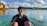 Smiling tourist enjoying a boat tour in turquoise Caribbean waters under a sunny sky.