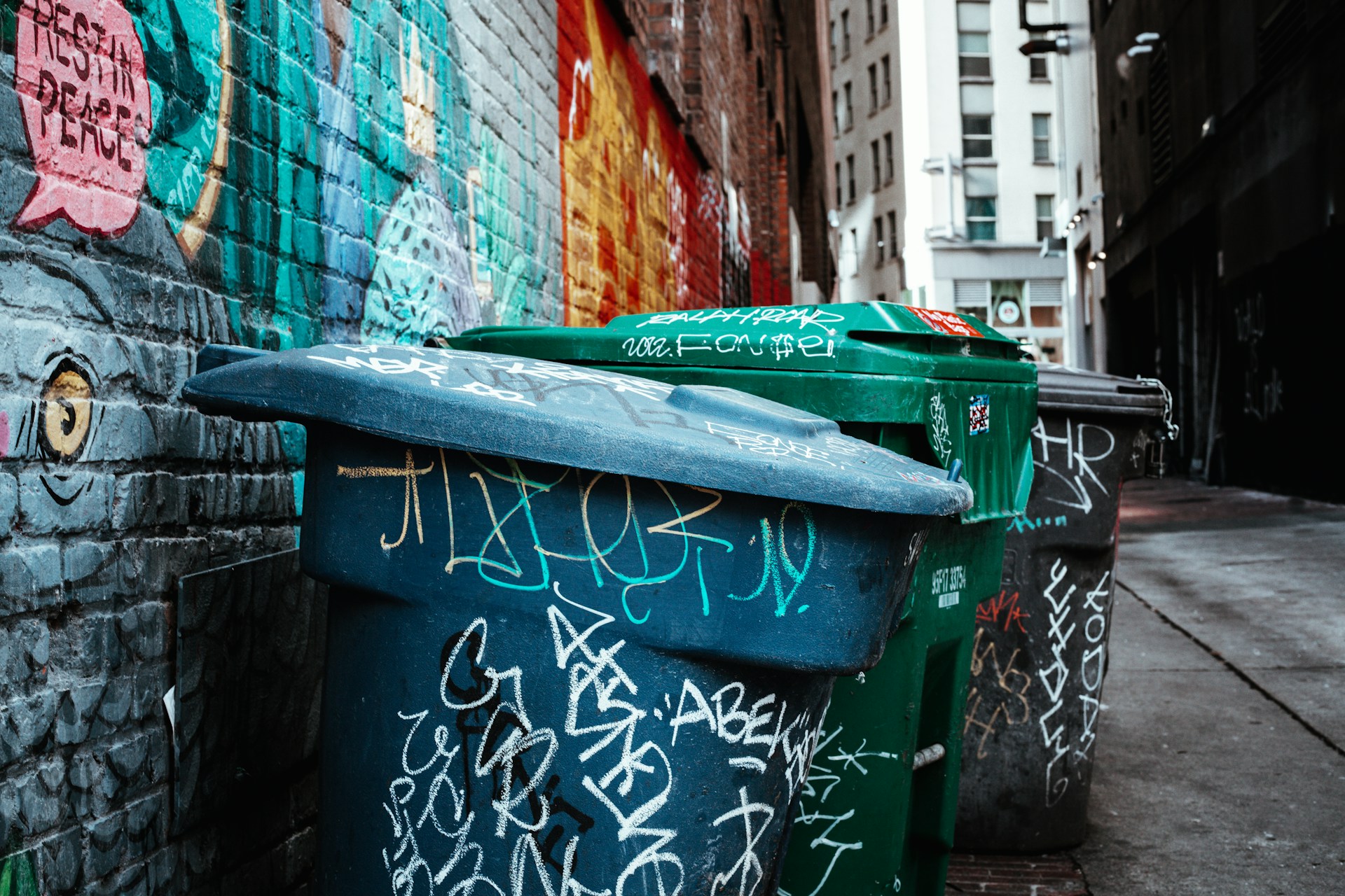 a green trash can on a sidewalk