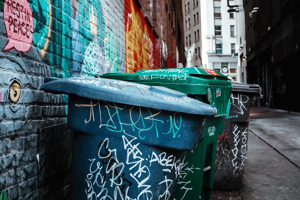 a green trash can on a sidewalk