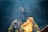 A firefighter wearing protective gear and a helmet is surrounded by smoke and flames, with sparks floating in the air.