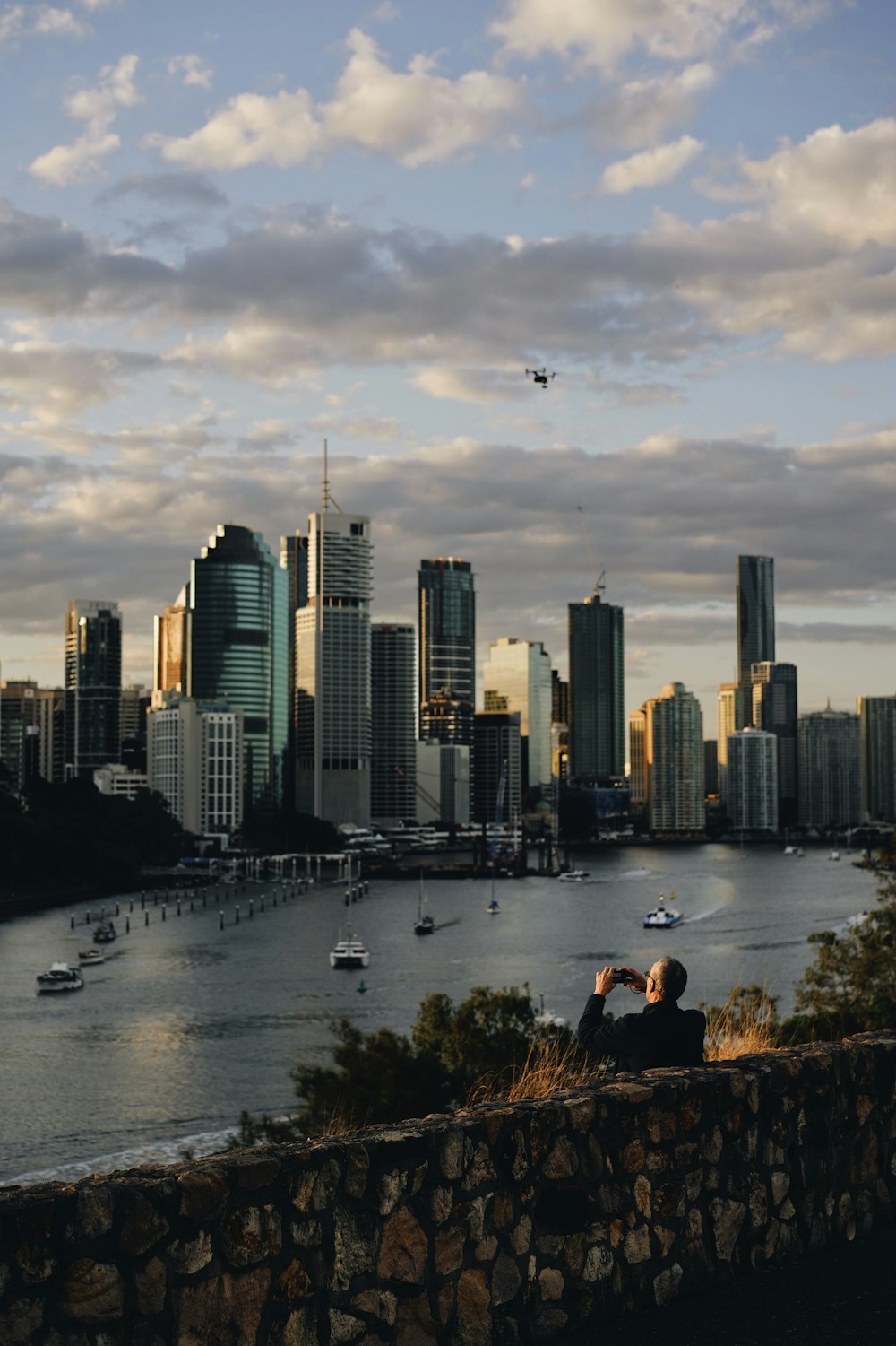 a person sitting on a ledge overlooking a city and water