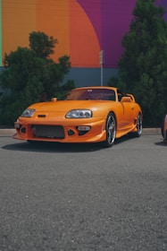 A bright red sports car ready for a coastal road trip, parked near a vibrant Miami street mural.