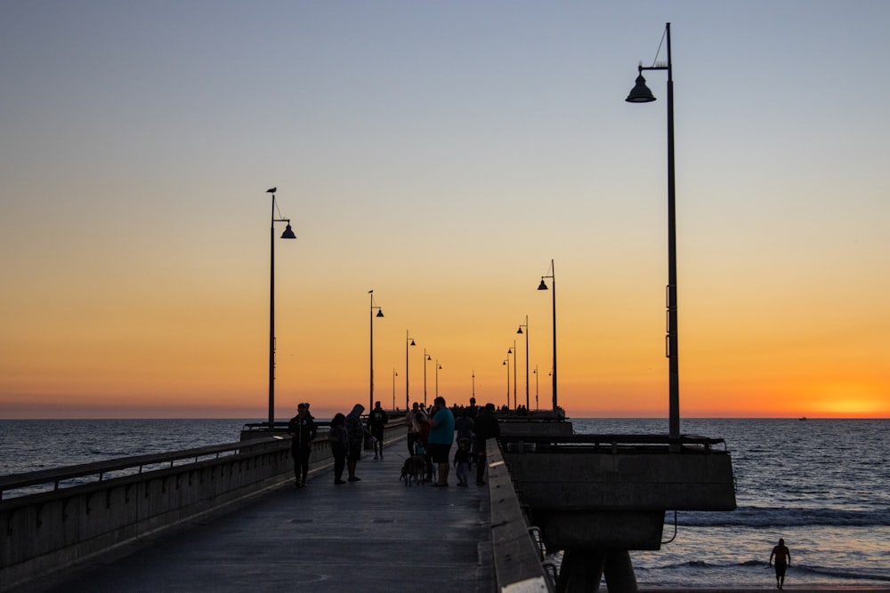 a group of people walking on a pier by the water