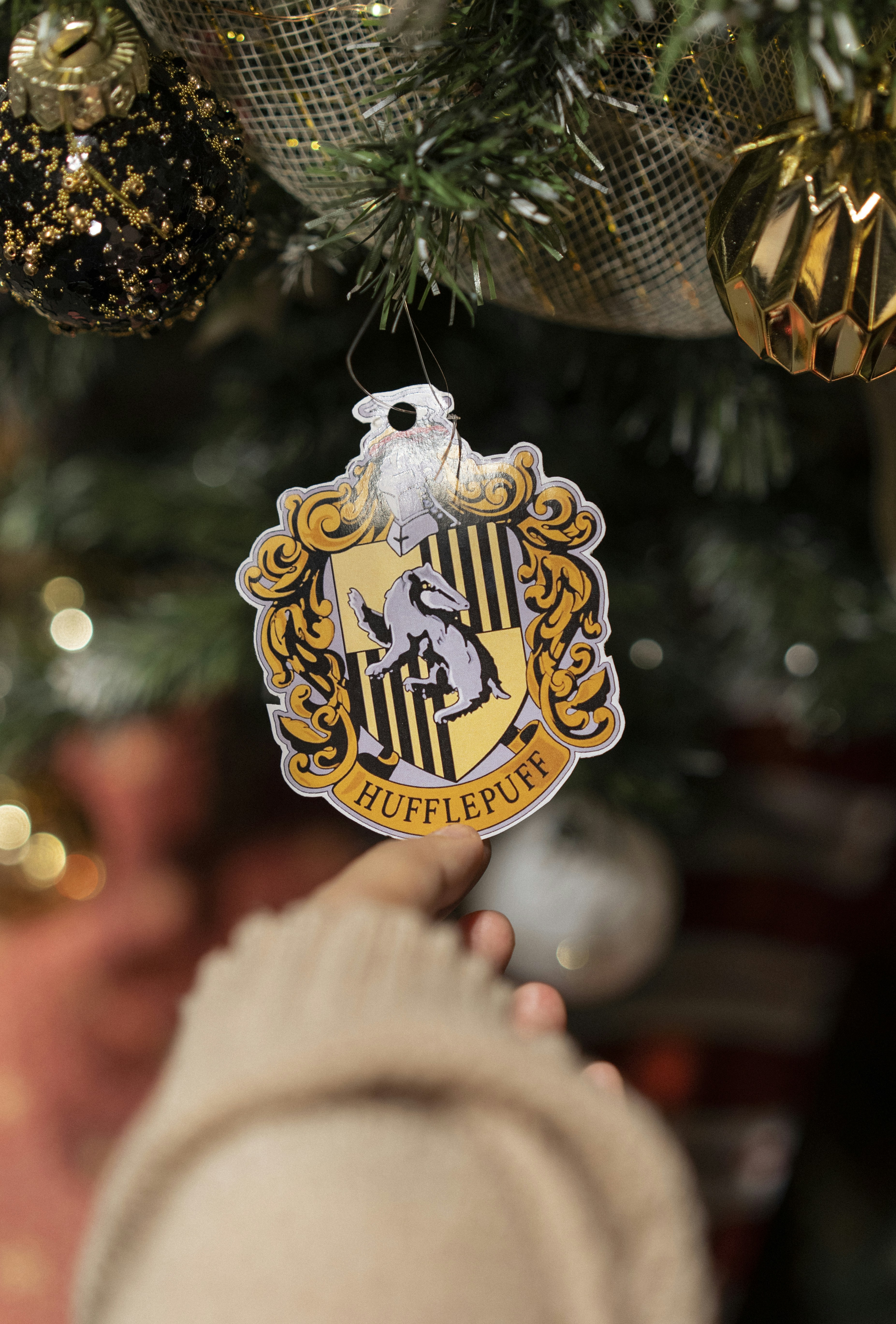 A hand holding a gold and black decorated tree with a gold and white ...