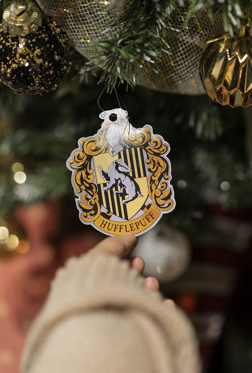 a hand holding a gold and black decorated tree with a gold and white emblem