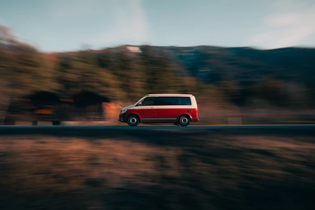 A white, blue, and red delivery van driving on a scenic Slovak road.