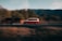 A red and white van is in motion, captured with a motion blur effect against a backdrop of blurred trees and mountain scenery.