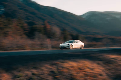 Mach1 vehicle speeding along a winding mountain road at sunset.