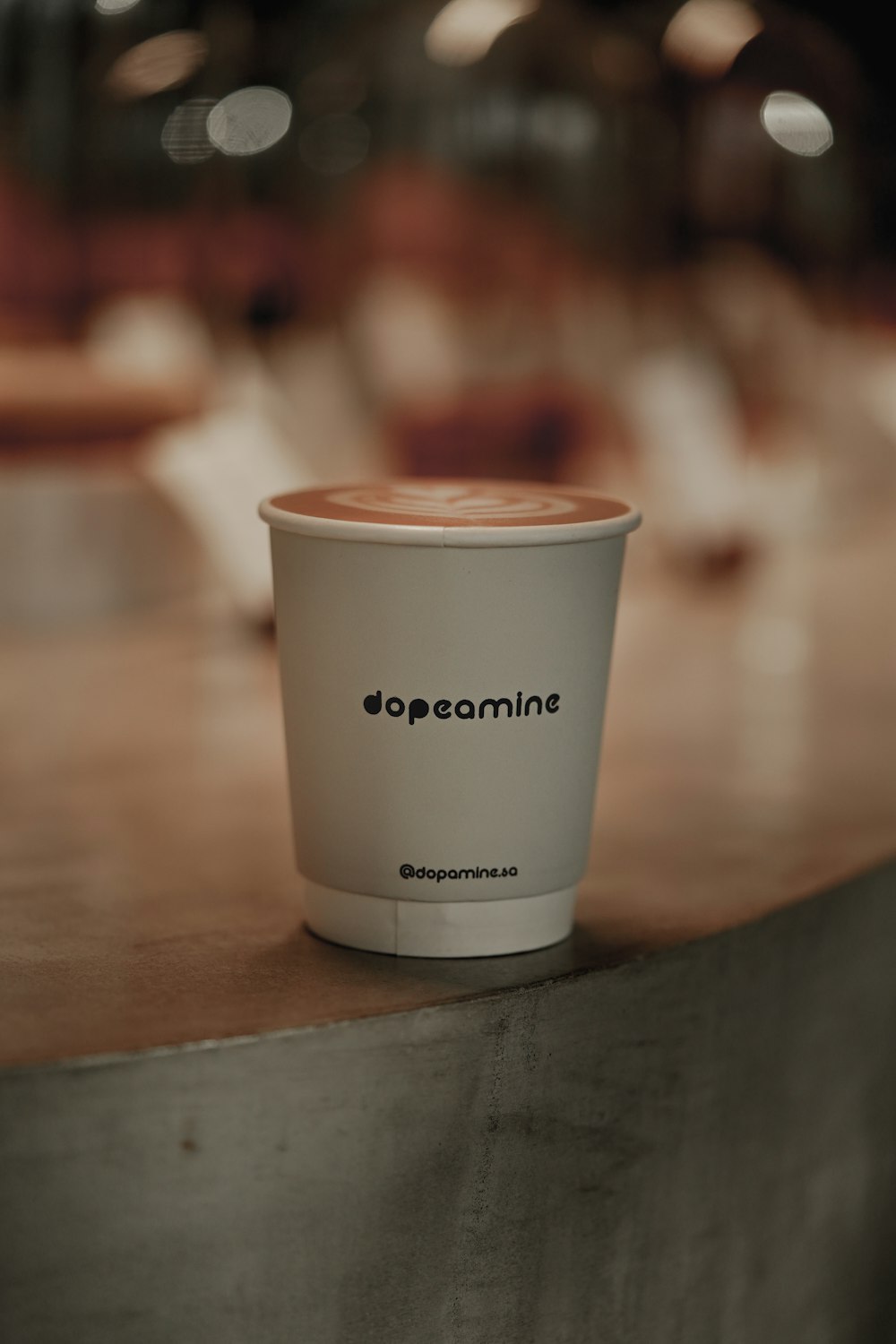 a white cup with a brown lid