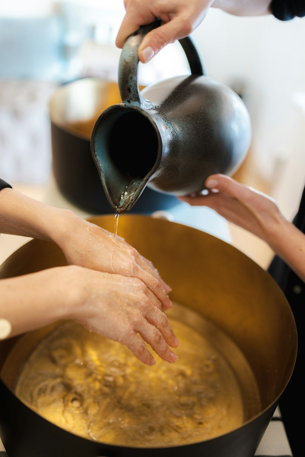 hands pouring liquid into a pot