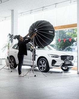 Technician adjusting lighting and technology settings in a sophisticated automotive showroom.