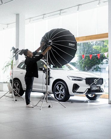 Technician adjusting satellite radio equipment inside a modern vehicle under soft workshop lighting.