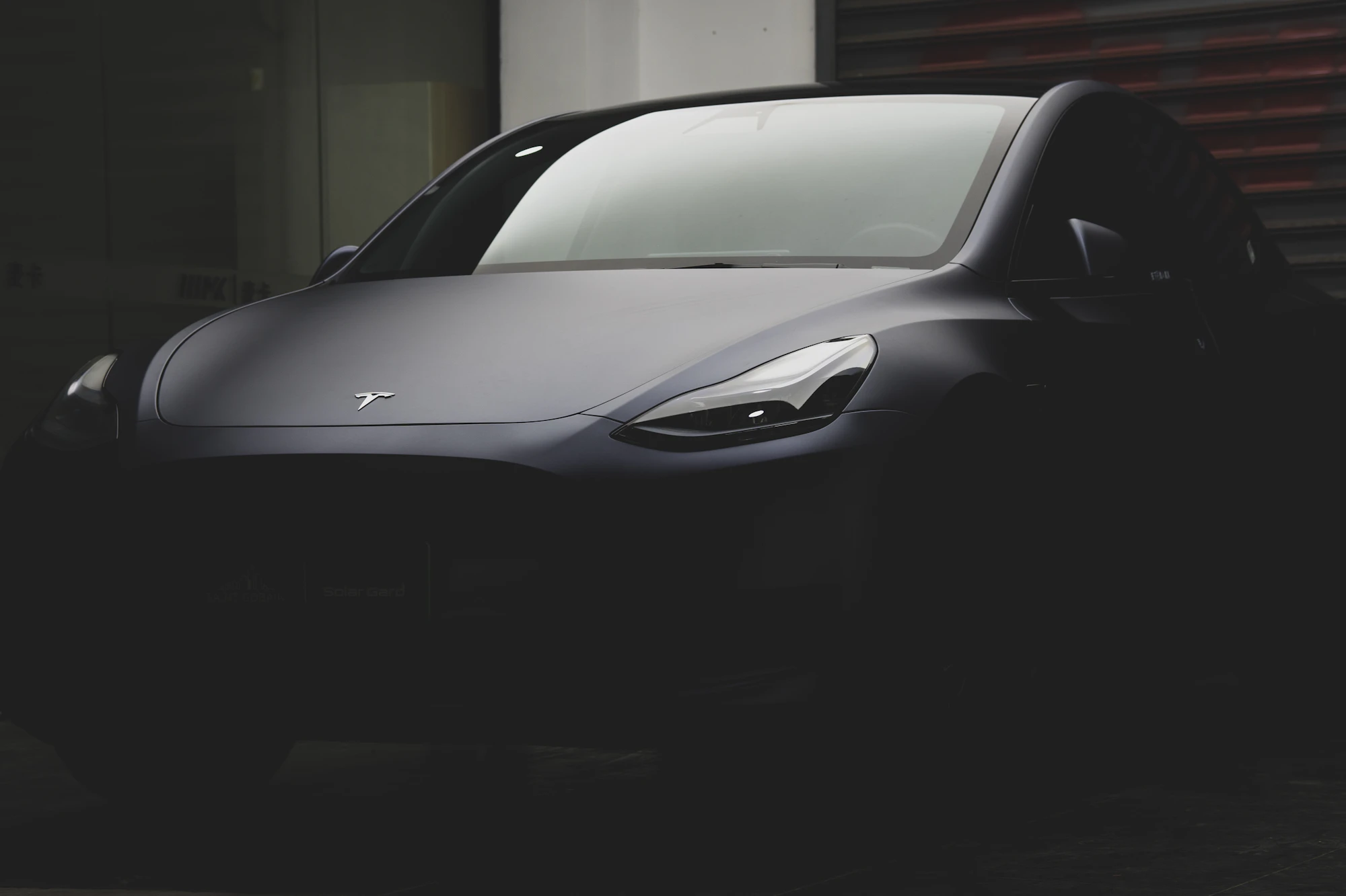 A dark Tesla Model Y lit from one side