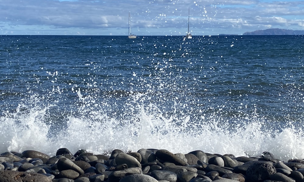 Una playa rocosa con barcos en el agua