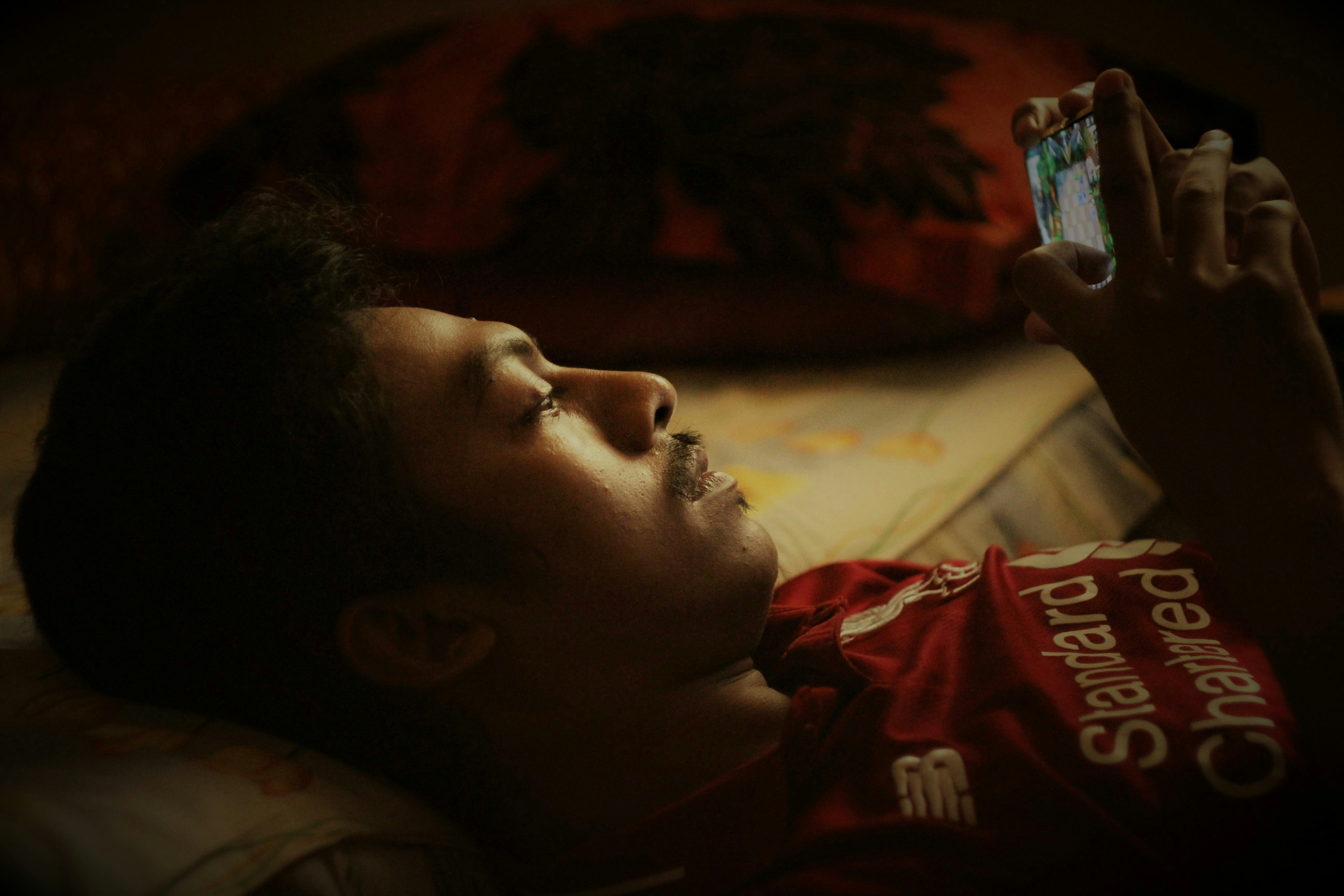 seseorang berbaring di tempat tidur dan memegang ponsel
