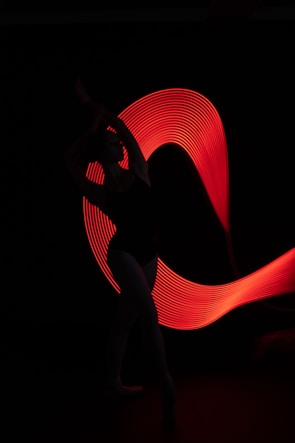 Close-up of a dancer’s silhouette against a deep black background with glowing neon accents.