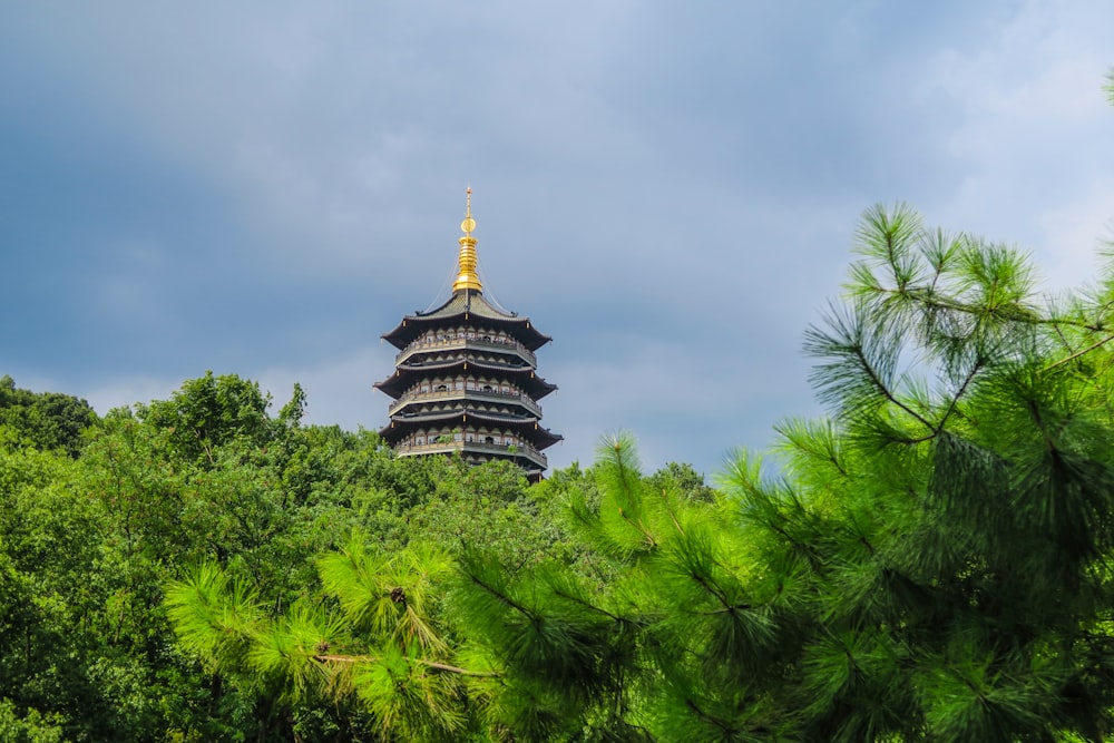 a tall building behind trees with Leifeng Pagoda in the background