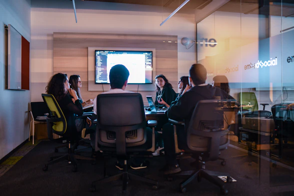 a group of people sitting in chairs in front of a projector screen