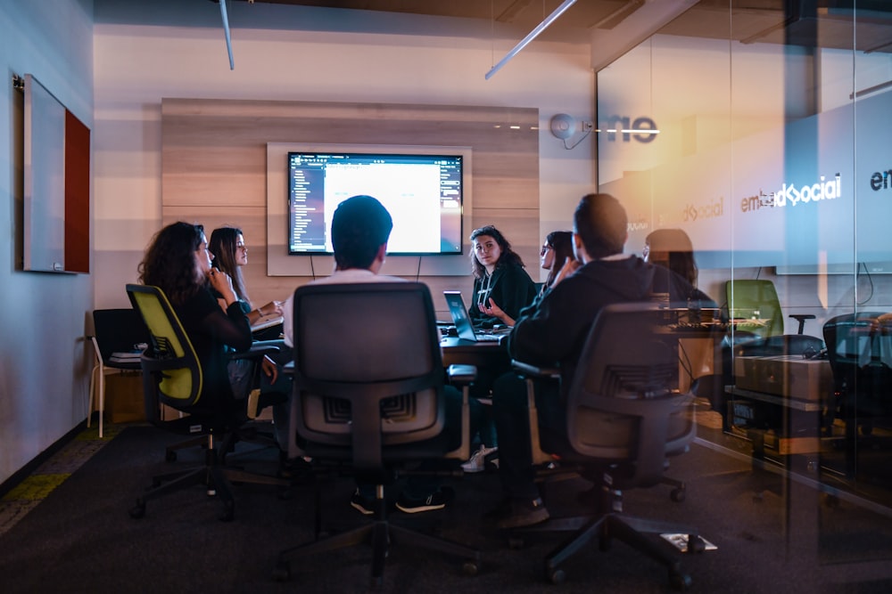 a group of people sitting in chairs in front of a projector screen