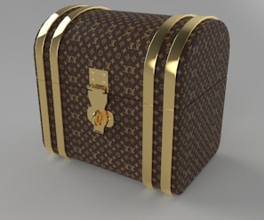 A luxury chest with a curved top, adorned with a recognizable brown and gold monogram pattern. The chest features gold-colored metal bands and a central lock, giving it an elegant and sophisticated look.