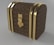 A luxury chest with a curved top, adorned with a recognizable brown and gold monogram pattern. The chest features gold-colored metal bands and a central lock, giving it an elegant and sophisticated look.