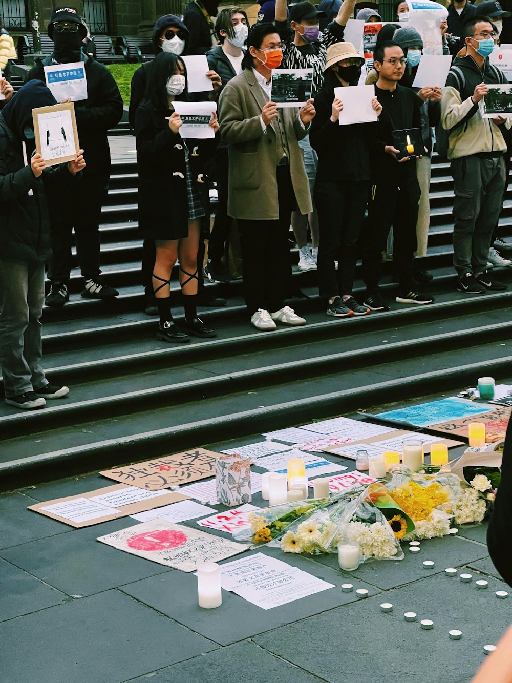 a group of people standing on a street with flowers and signs