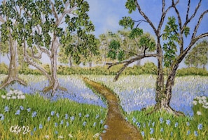 A serene landscape painting depicting a path winding through a vibrant field of wildflowers, surrounded by lush trees under a clear blue sky. The flowers are predominantly blue, interspersed with green grass. The trees have thick trunks and branches with abundant green leaves.