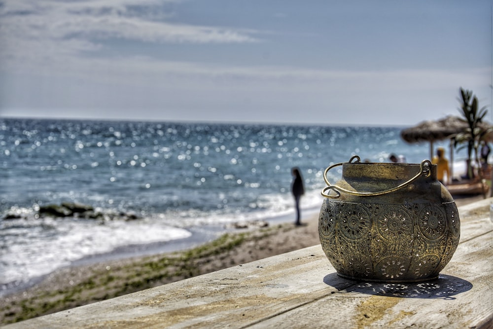 a pot on a wood surface overlooking a beach and ocean