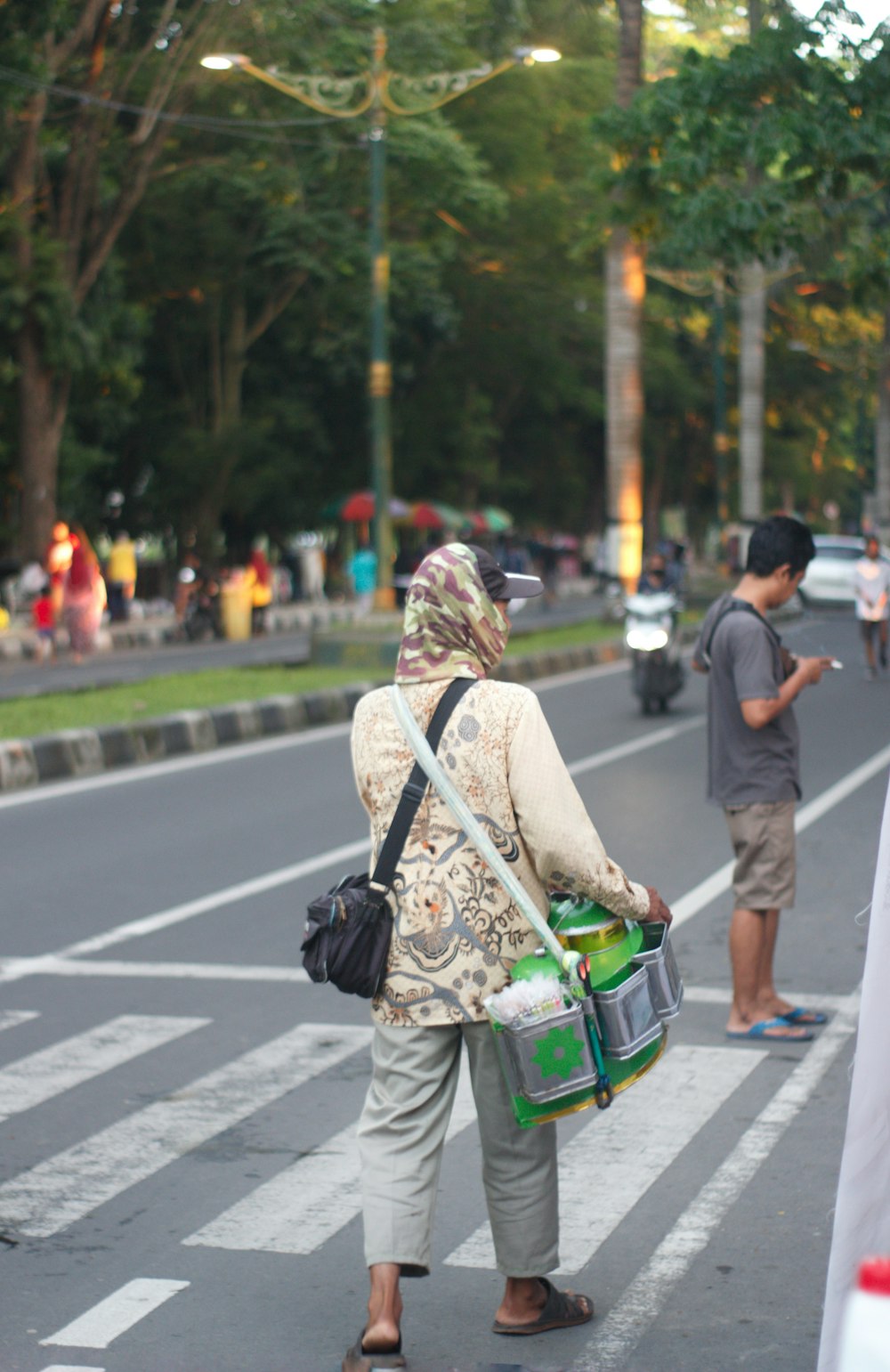 uma pessoa carregando uma bolsa andando através de uma faixa de pedestres