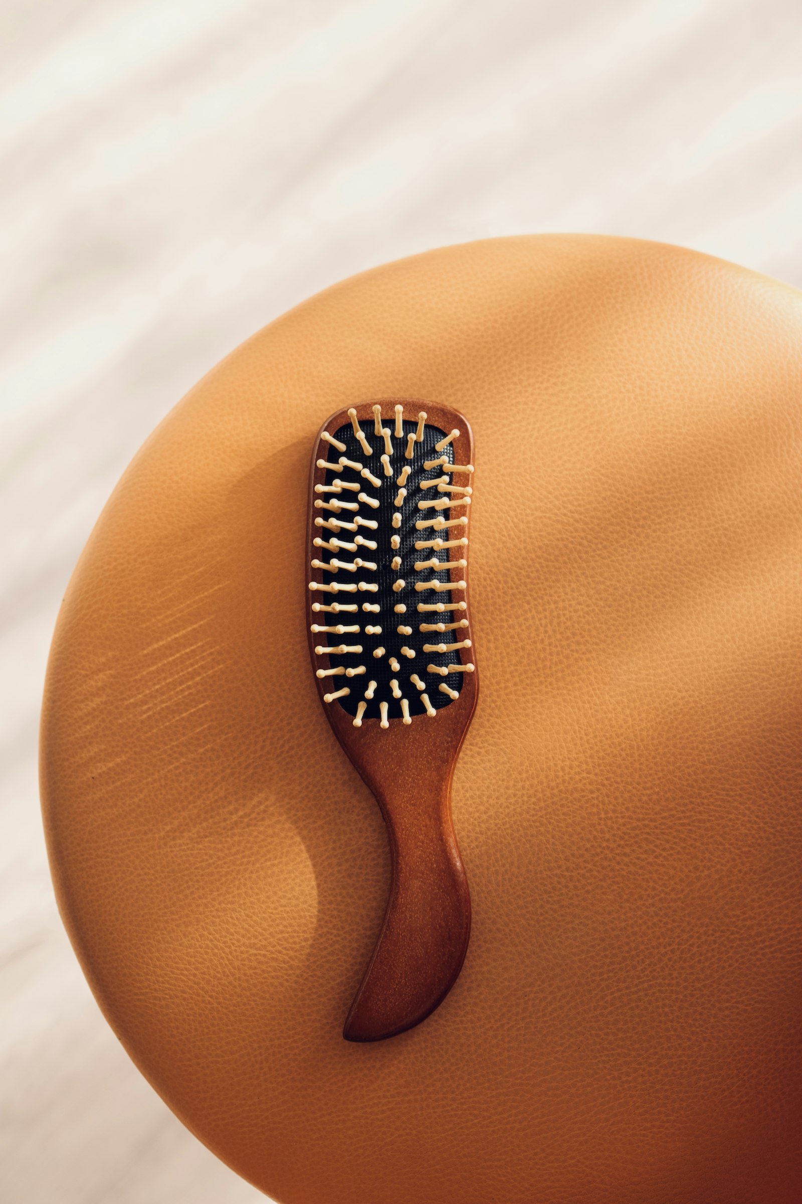 Une petite brosse à cheveux en bois posée sur un tabouret orange