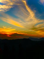Colorful landscape painting capturing a sunset over mountains.