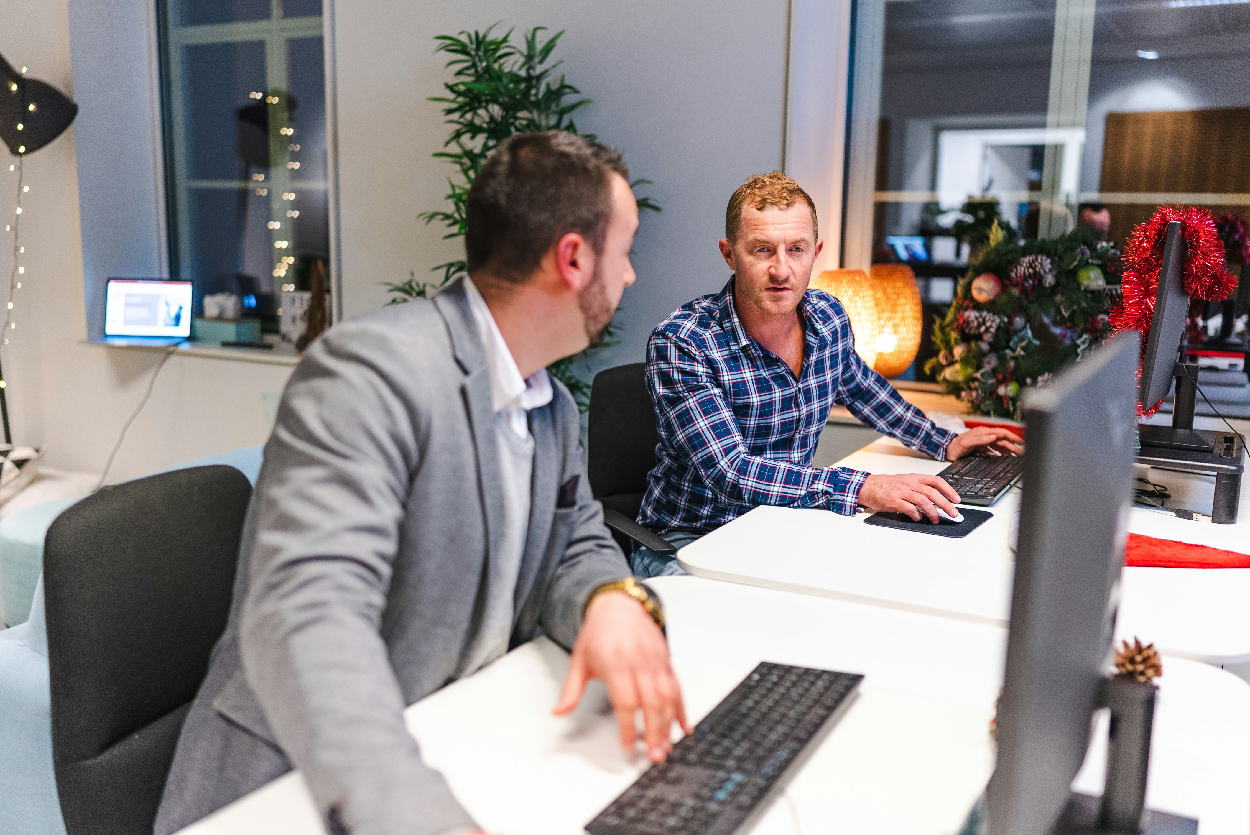 una persona seduta a una scrivania con una persona seduta a un computer