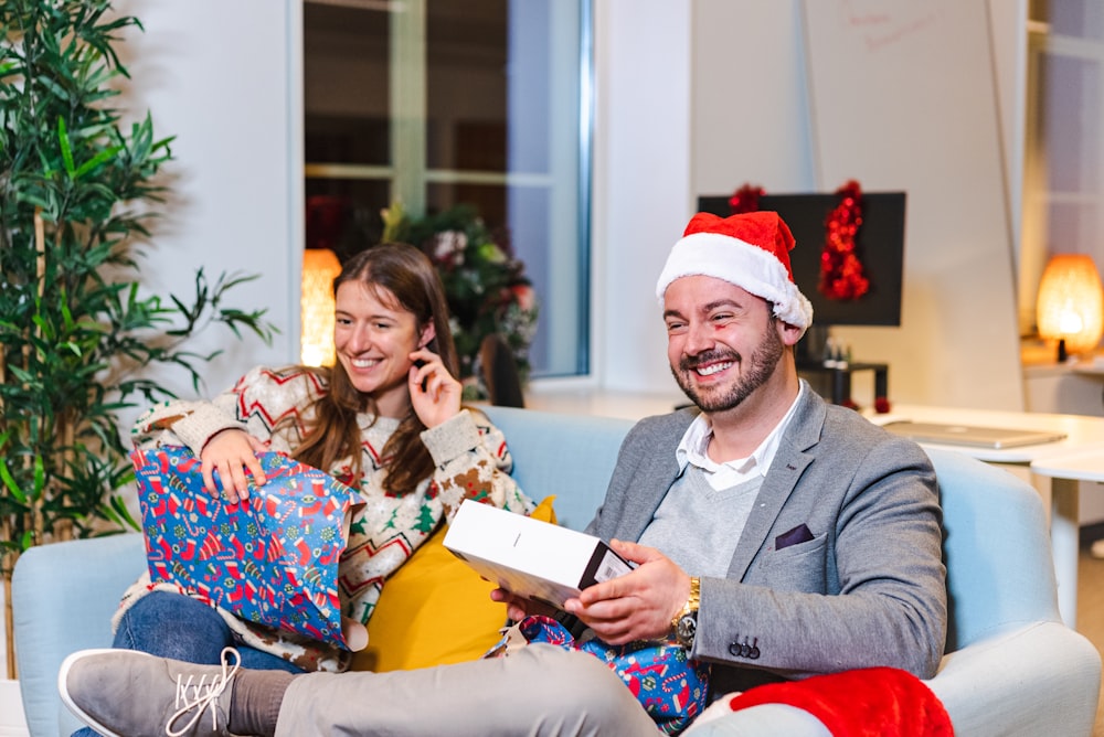 a man and a woman sitting on a couch with a christmas tree