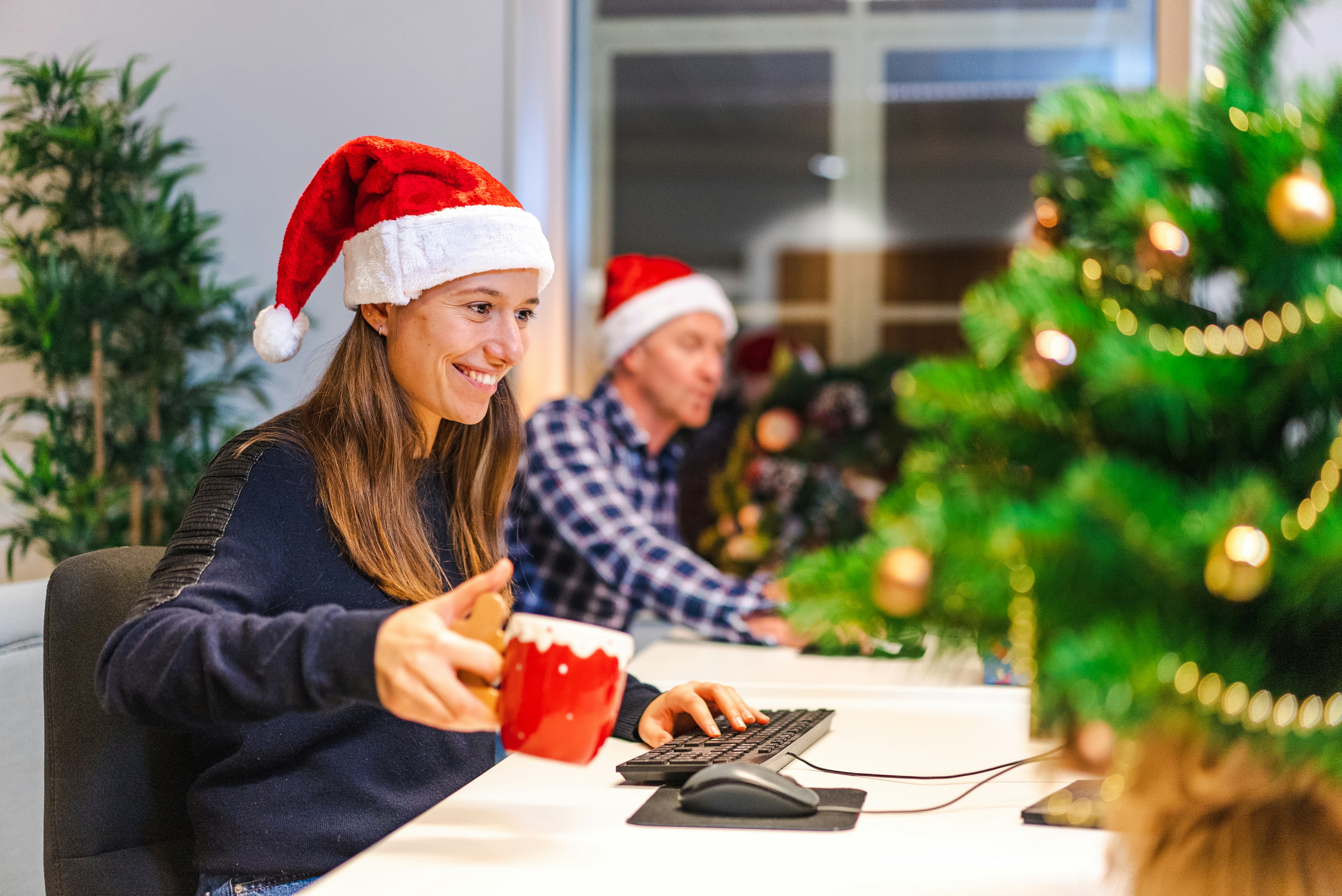 a woman and a man wearing santa hats and sitting at a table