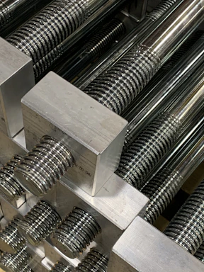 Close-up of shiny aluminum extrusions stacked neatly in a workshop.