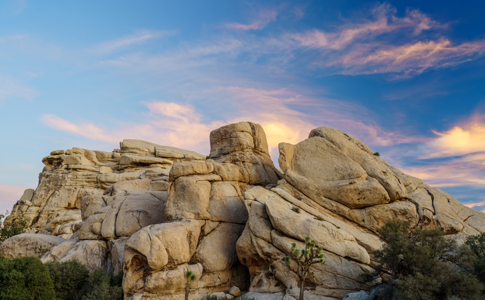 a rocky mountain with trees and a sunset