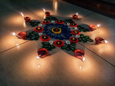 Colorful rangoli design with flowers and lamps glowing softly in the evening light.