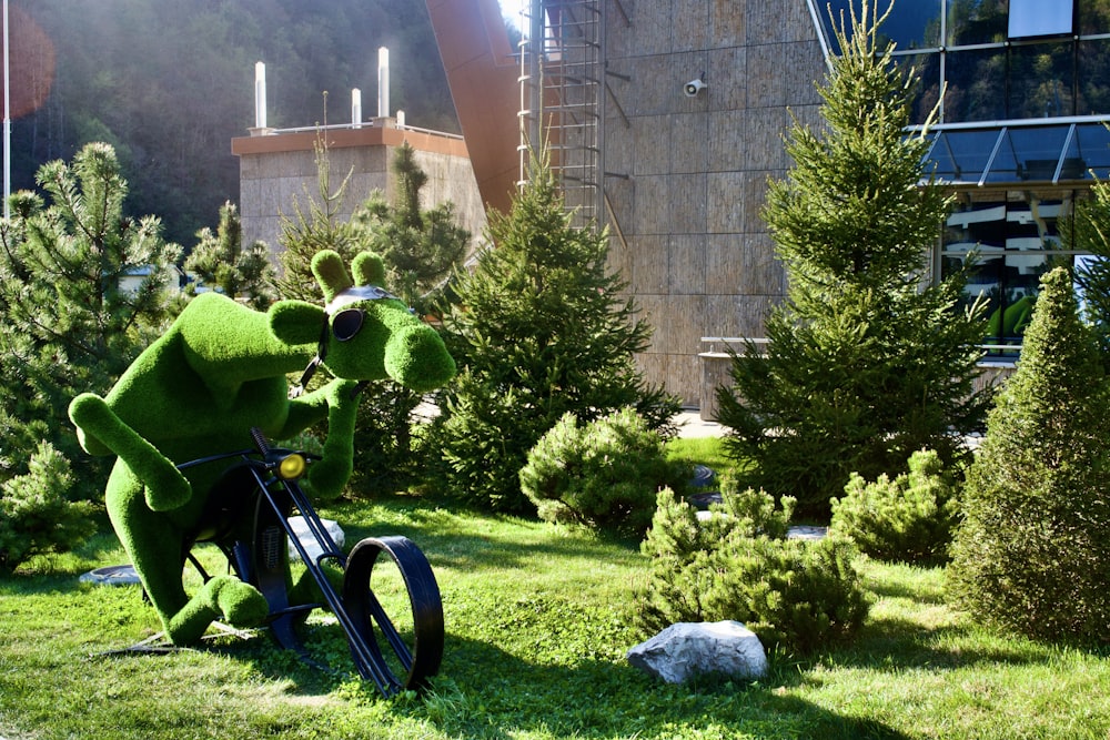 a green dinosaur statue in a garden