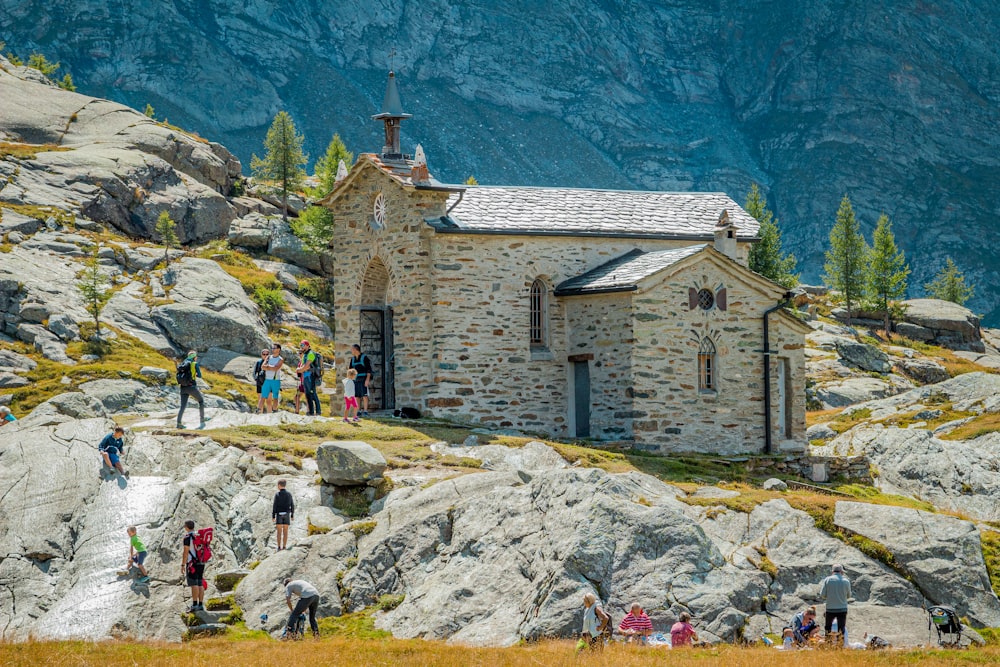 a group of people standing on a rocky hillside with a building on top