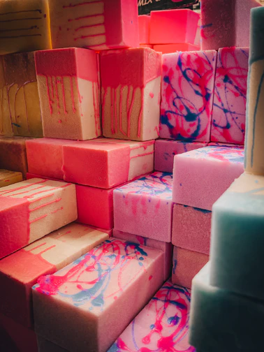 Close-up of colorful soaps and bath bombs stacked artistically with fresh flowers.