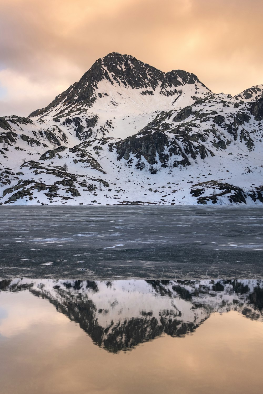 a snowy mountain with a body of water below