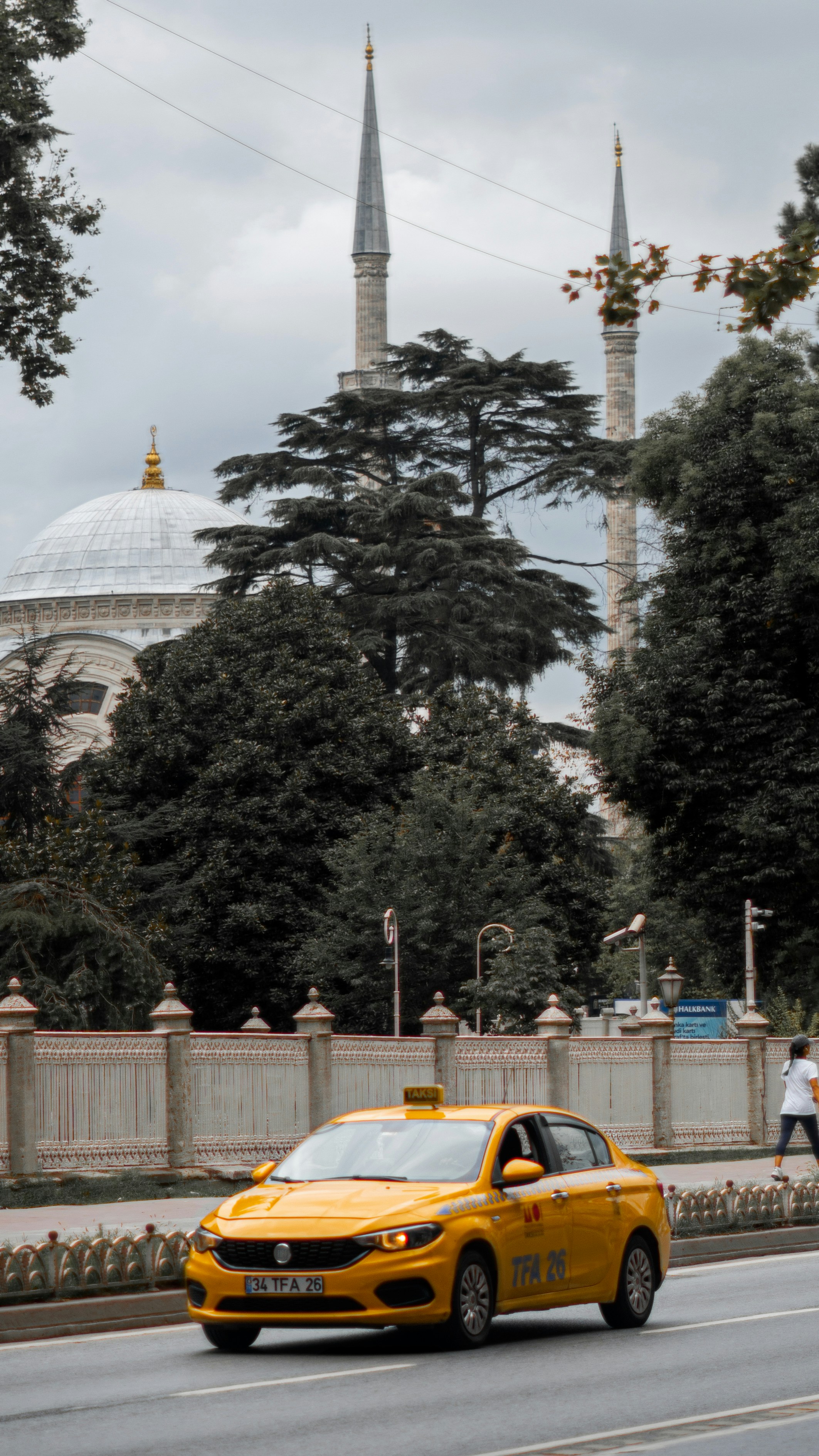 a yellow car on a road with a building in the background
