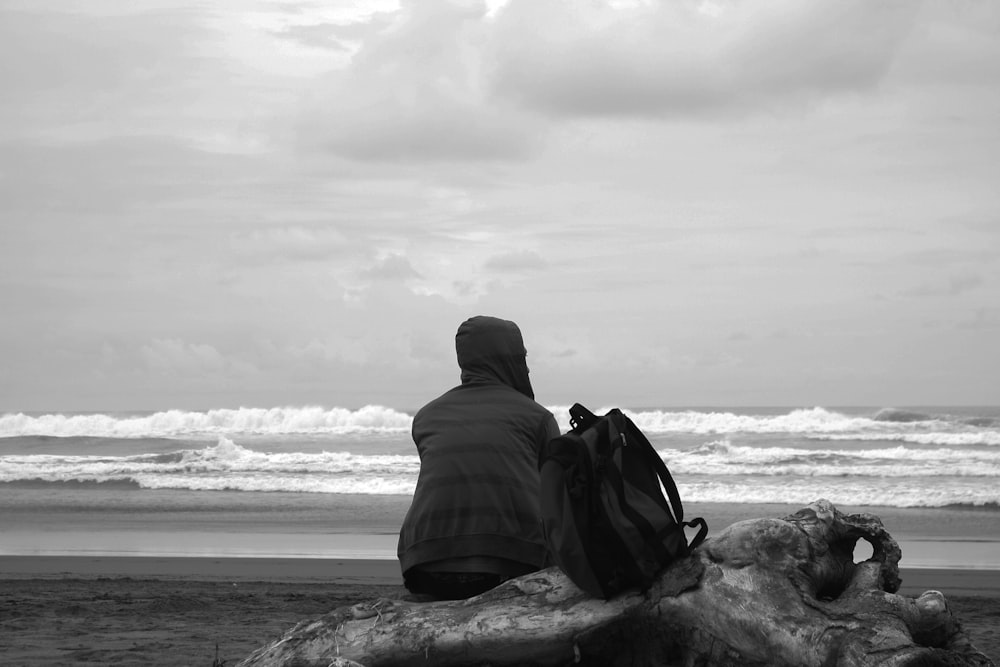 a person sitting on a rock looking at the ocean