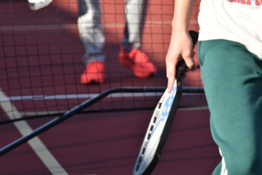 a pickleball player holding a paddle with a net in the background
