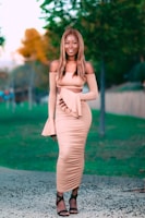 A woman dressed in a chic, contemporary dress from Walaa's women's section, smiling while walking through a sunlit park.