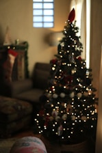 A softly lit living room decorated with twinkling Christmas lights and a glowing fireplace.